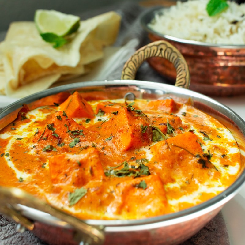 Balti curry served in a traditional copper karahi with rice and naan