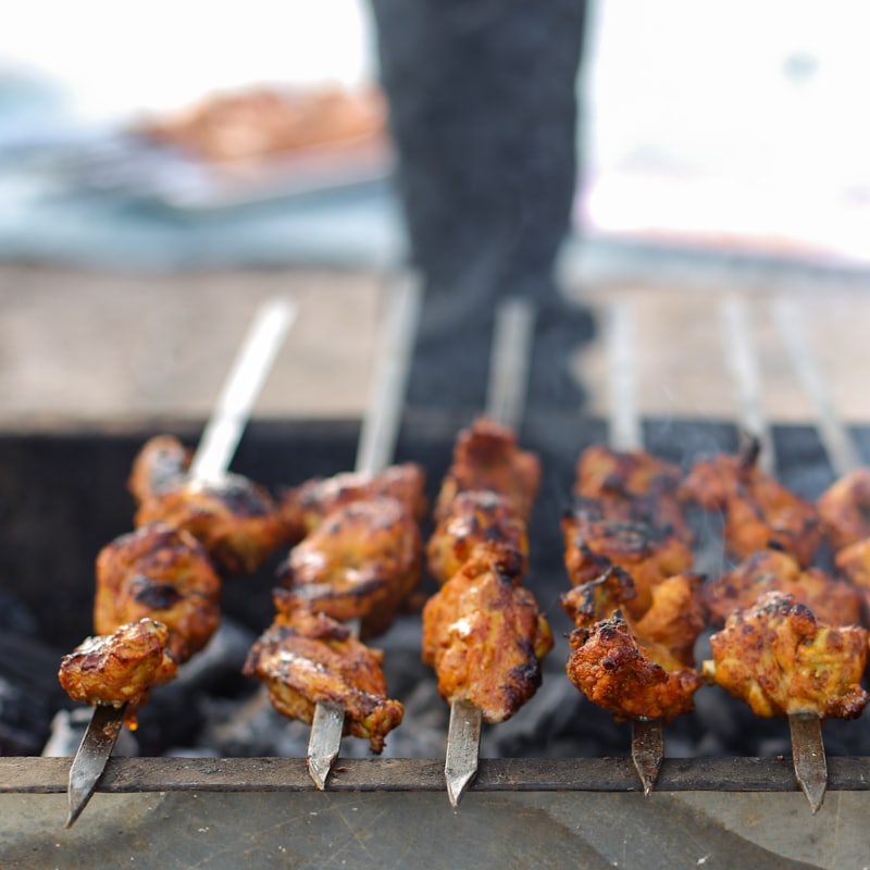 Marinated chicken skewers grilling over open coals